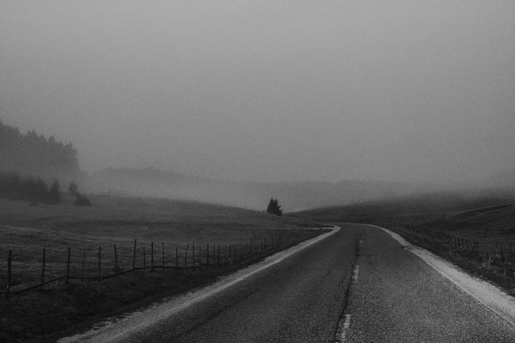 Country road against sky during foggy weather