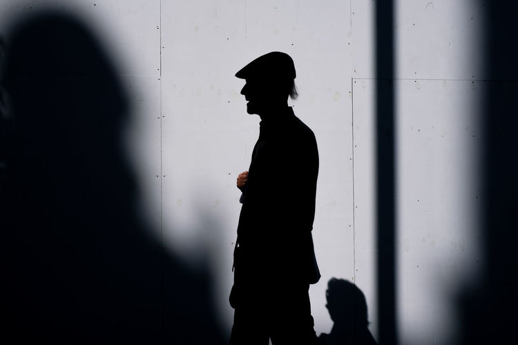 Side silhouette view of old man with cap