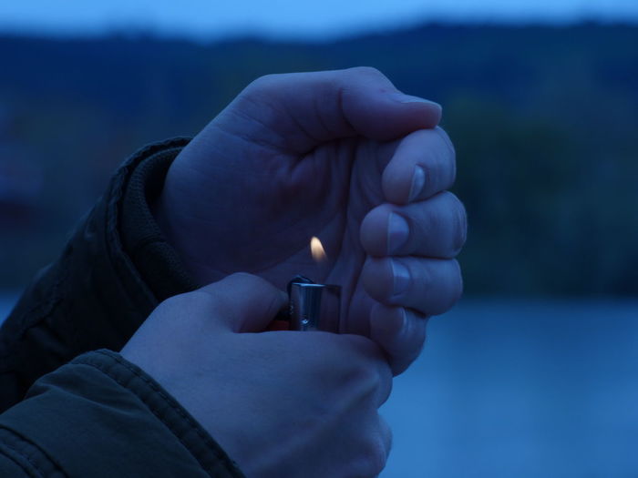 Cropped hand holding illuminated cigarette lighter