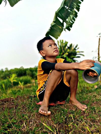 Young man looking away while sitting on land