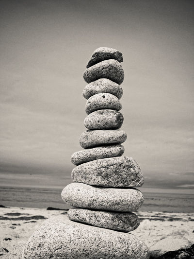 Stack of pebbles at beach against sky