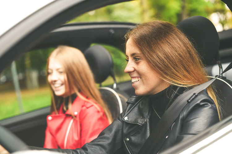 Trendy girls sitting in the car. smiling teen with friend drive car. young women enjoying free time