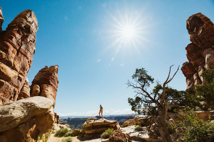 Female hiker climbs sandstone under bright midday desert sun