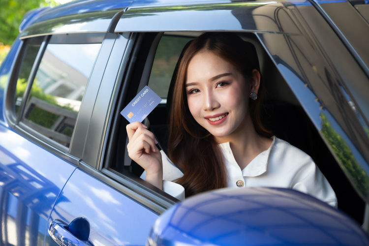 Portrait of smiling young woman holding car