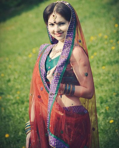 Portrait of smiling young woman in sari standing on field