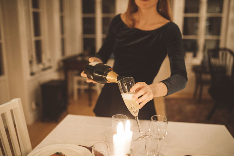Mid section of woman pouring champagne