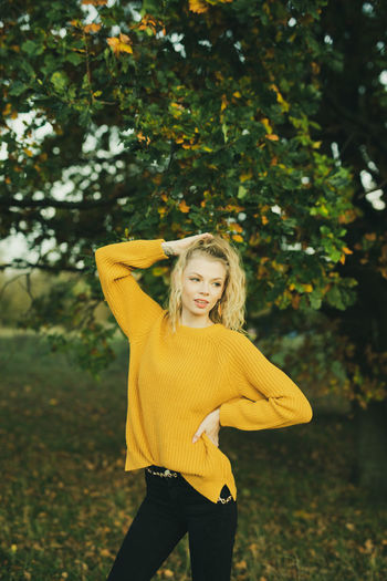 Portrait of young woman standing against yellow tree