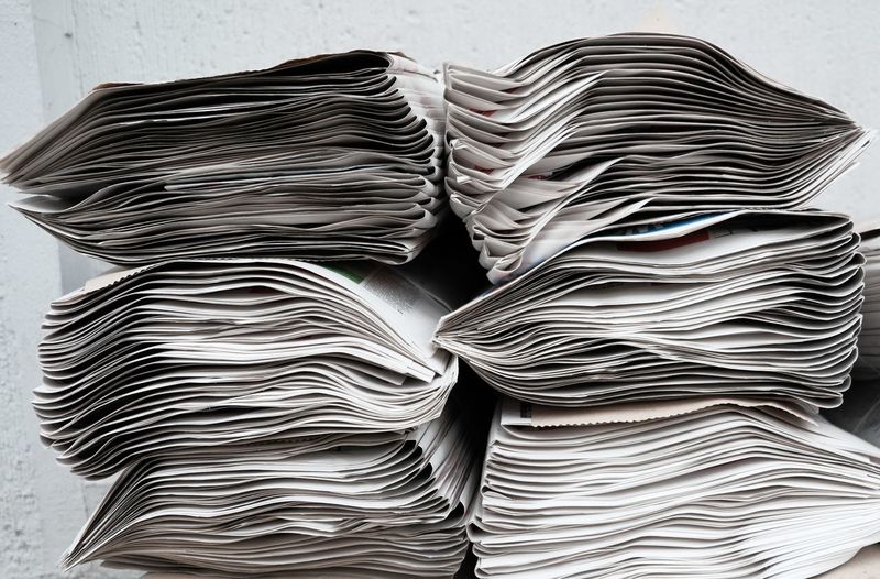 Close-up of stacked newspapers over white background