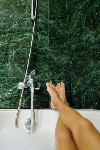 Low section of  woman relaxing in bathtub