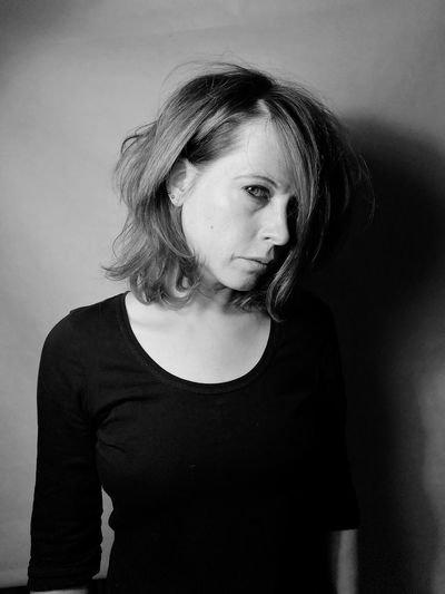Portrait of serious woman standing against wall