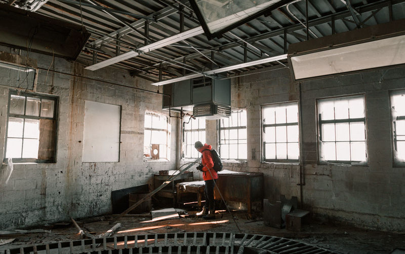 Side view of young man photographing in abandoned factory