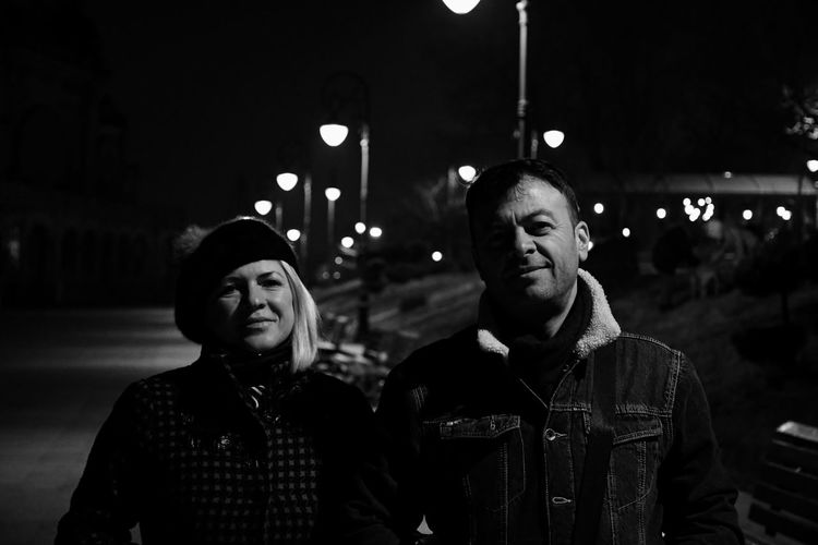 Portrait of smiling young couple standing outdoors at night