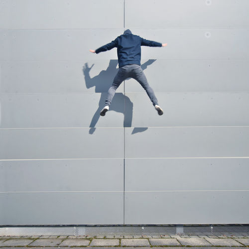 Full length of a man jumping against white wall