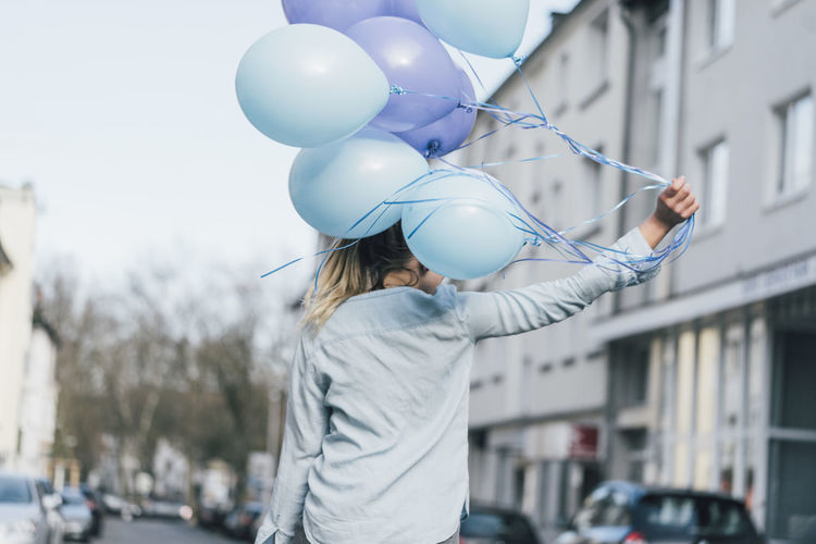 Back view of woman with blue balloons