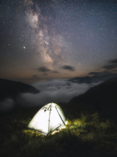 Night mountain landscape with tent. mountain peaks,fog in the valley,and milky way.