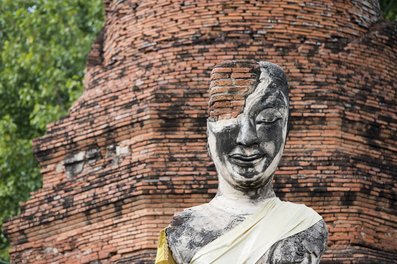 Low angle view of old damaged buddha statue and temple
