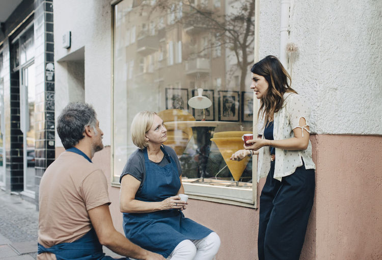 Male and female upholstery workers talking outside workshop