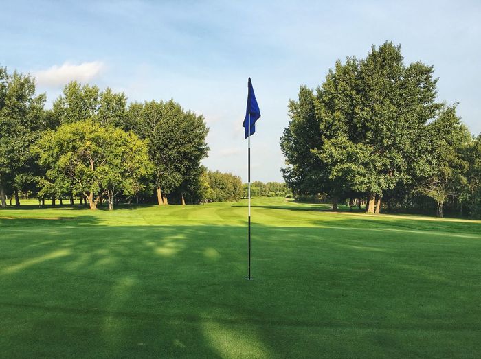 Flag on golf field against sky