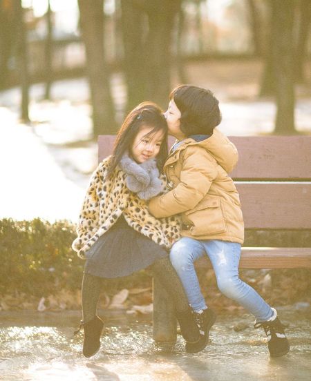 Children sitting on bench in winter