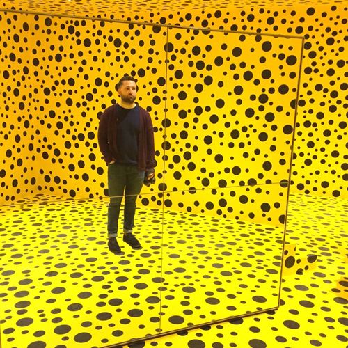 Full length reflection of man in mirror against polka dotted pattern