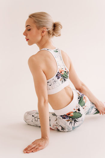 Side view of young woman doing yoga against white background