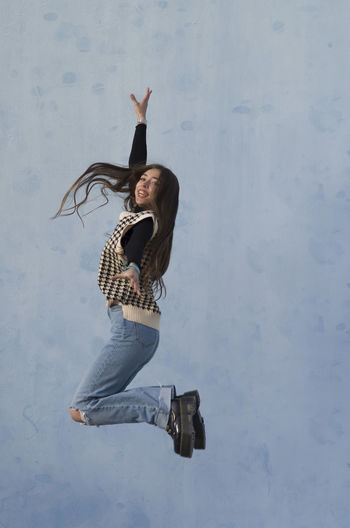 Low section of woman jumping against wall
