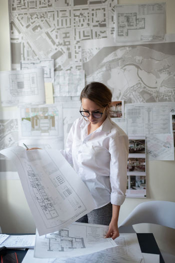Young female architect working with blueprints