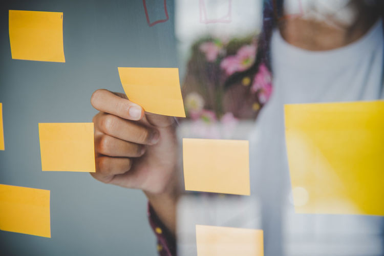 LOW SECTION OF WOMAN HOLDING YELLOW PAPER