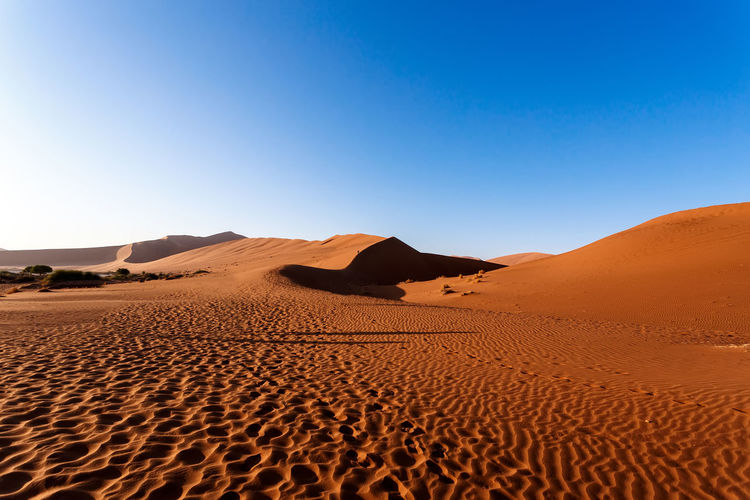 Sand dunes in desert against clear blue sky