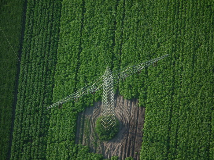 High angle view of electricity pylon on green farm field