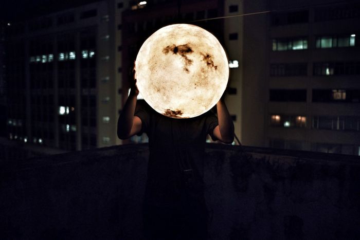 Man holding artificial moon at night
