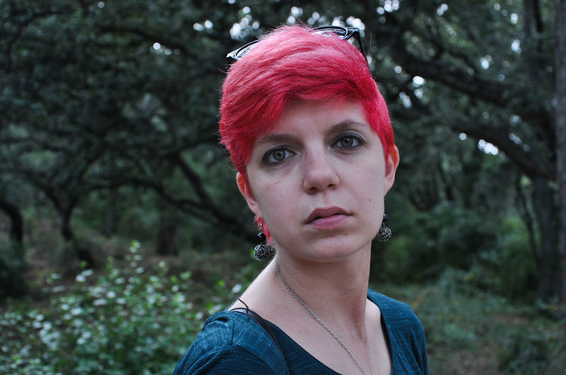 Portrait of young woman with dyed hair standing in forest