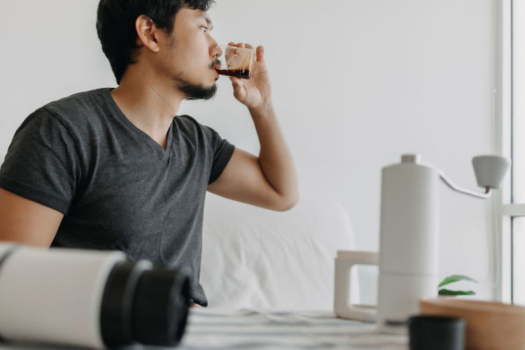 Side view of young man drinking coffee at home