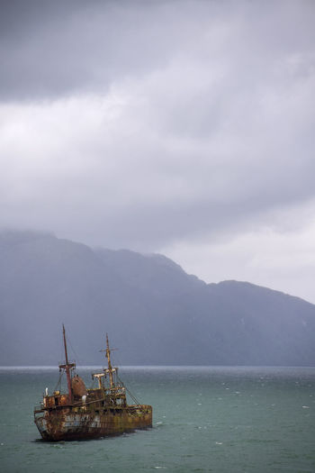 Sailboat in sea against mountains