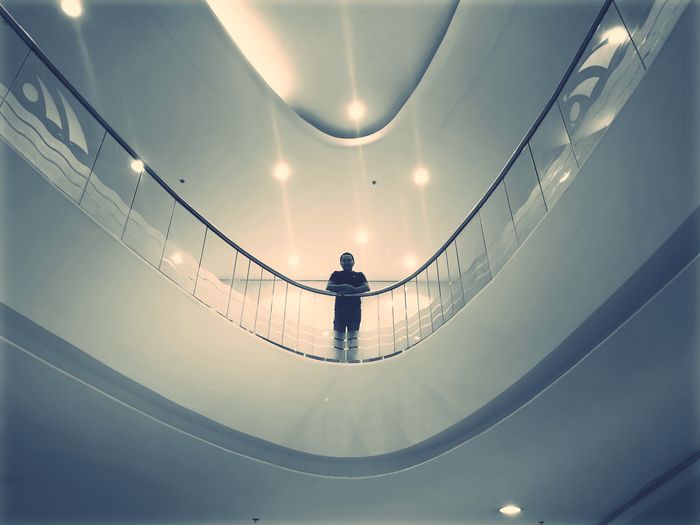 Low angle portrait of man standing by railing in building