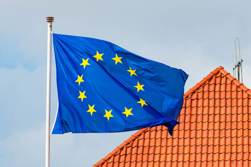 European union flag with roof of a house on background