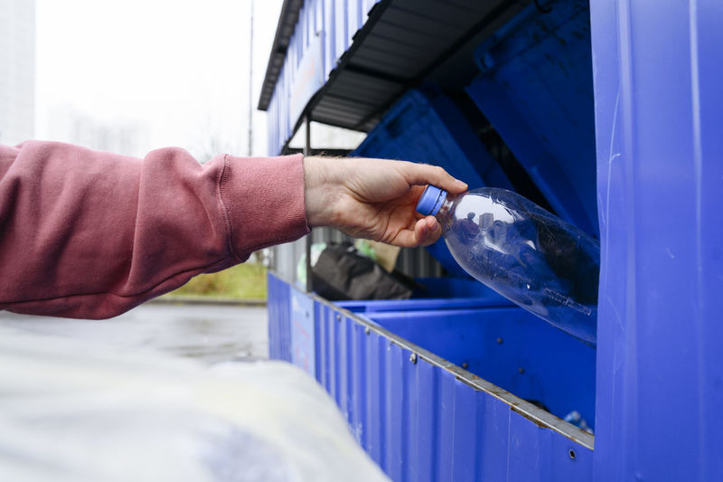 Hand of man throwing plastic bottle in trash