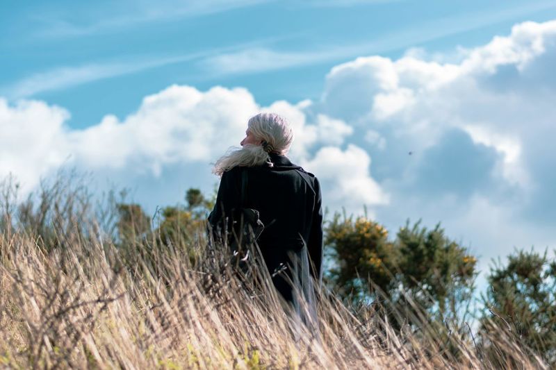 Rear view of woman looking into the distance against sky with large clouds