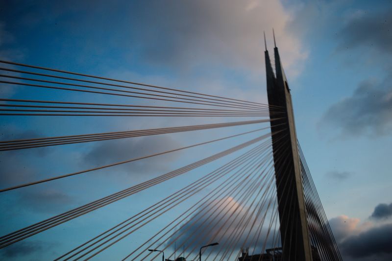 Low angle view of suspension bridge against cloudy sky