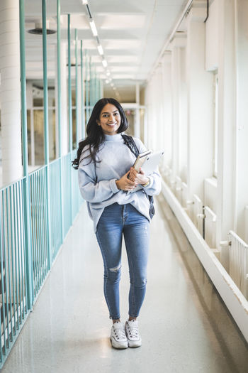 Portrait of young female student standing in corridor of university