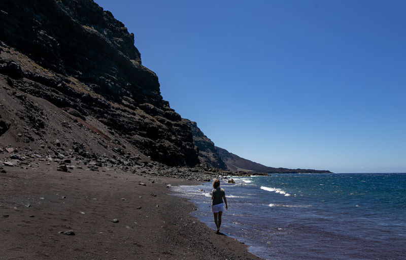 Woman on beach against clear blue sky