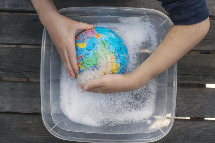 Cropped hands washing globe in container