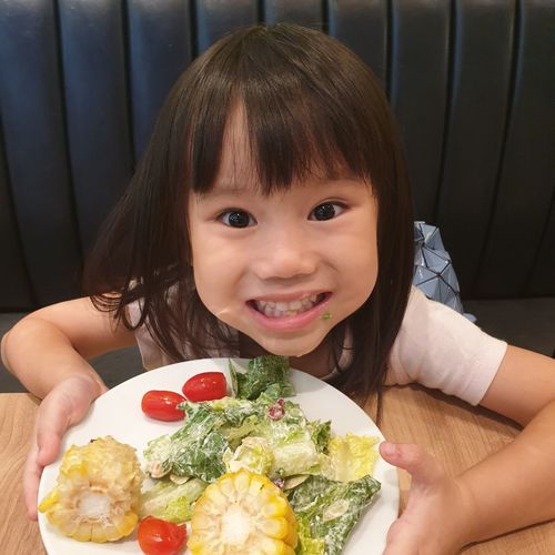High angle portrait of cute girl with salad on table in restaurant