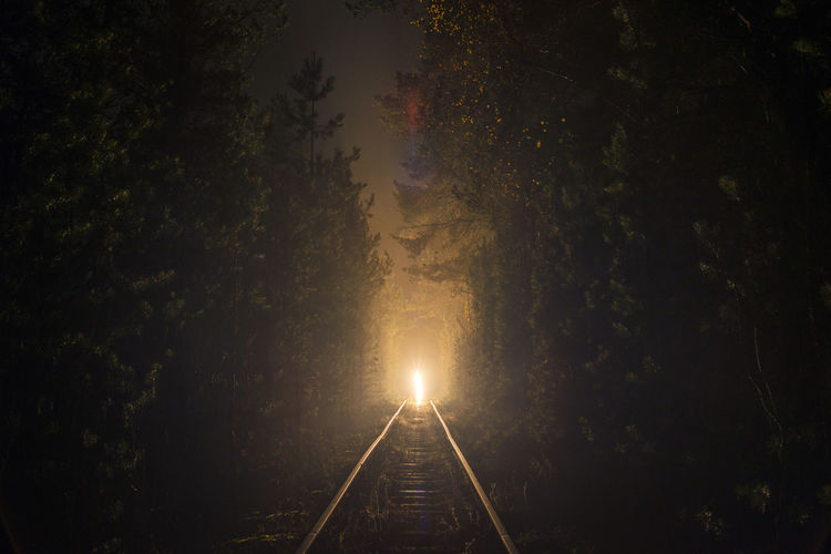 Illuminated railroad tracks against sky
