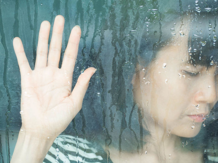 Close-up of woman hand on wet glass