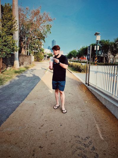 Full length of young man standing on footpath