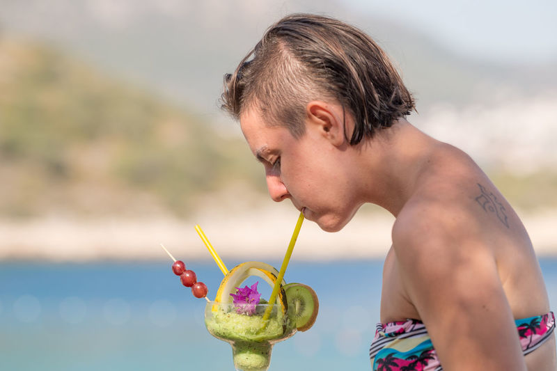 Side view of young woman drinking kiwi cocktail
