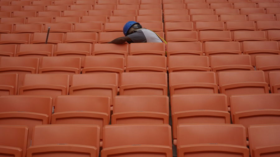 A worker between row of spectators seat in a stadium