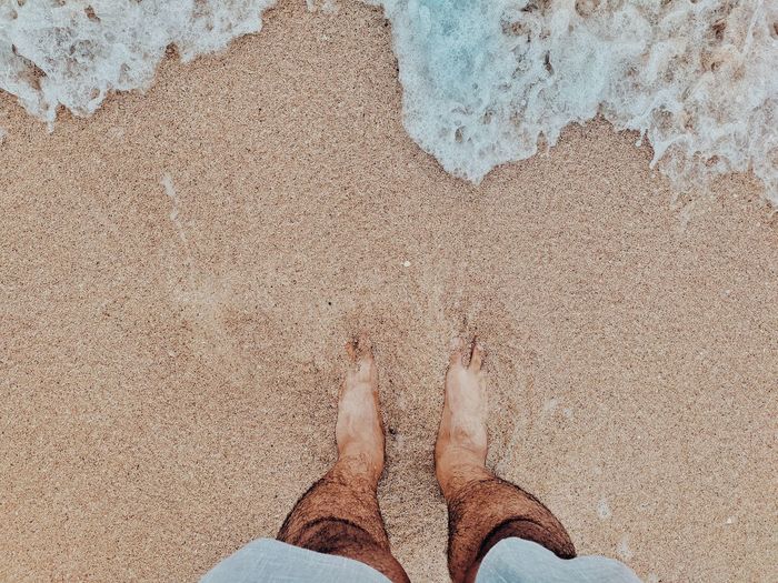 Low section of man standing on shore at beach