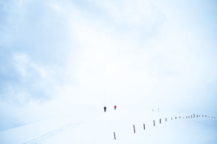Low angle view of people on snow against sky reaching summit